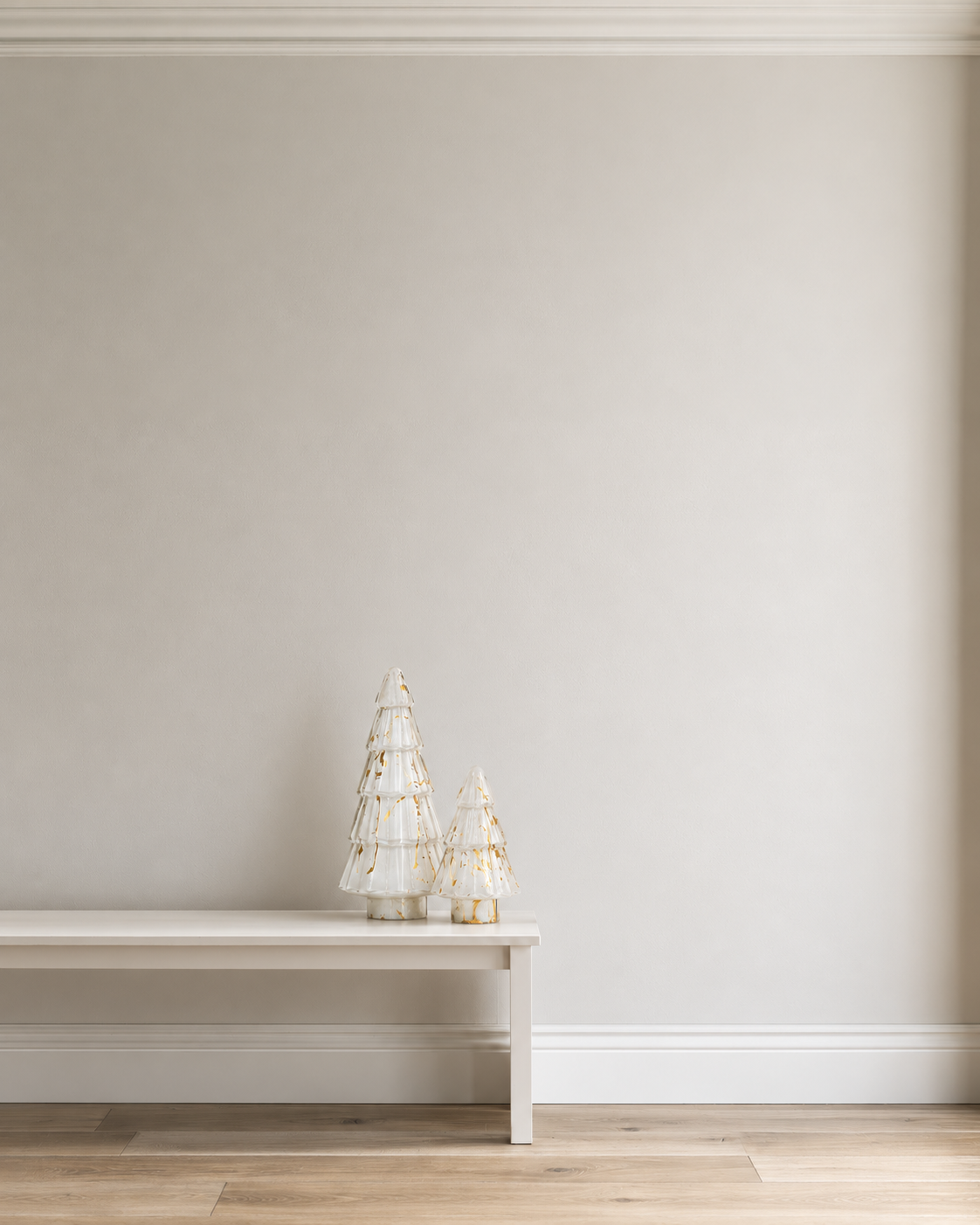 Gold paint splatter glass trees in 15cm and 31cm standing on a low white bench against a plaster wall