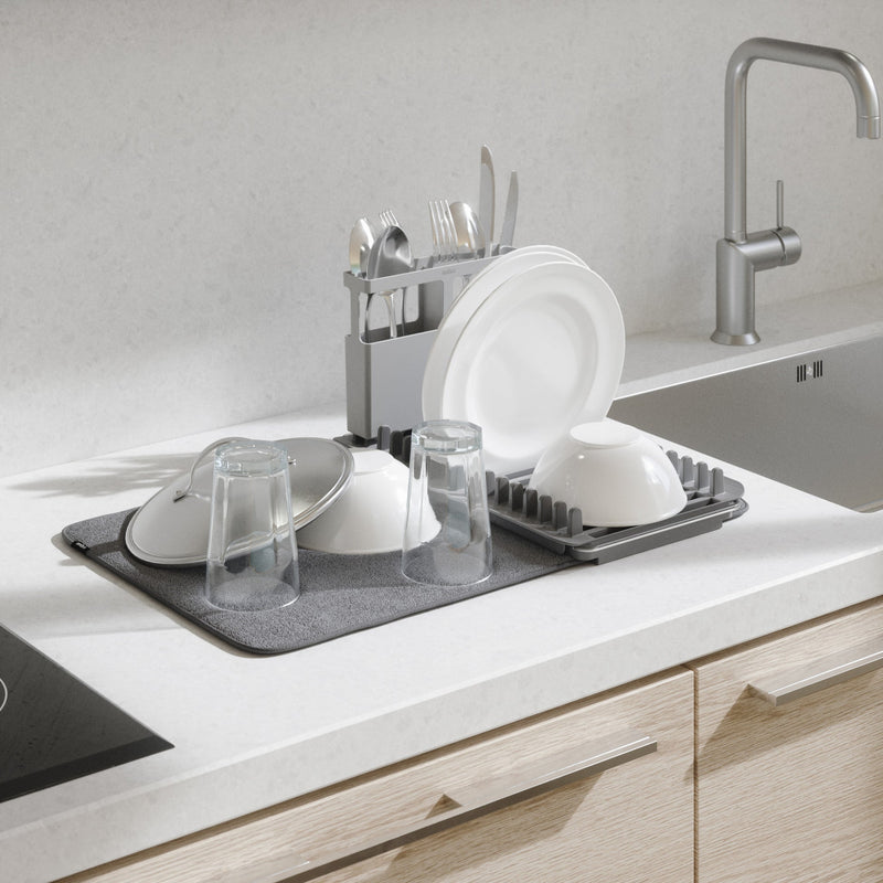 A kitchen sink with a Umbra UDry Over The Sink Dish Rack and glasses on it.