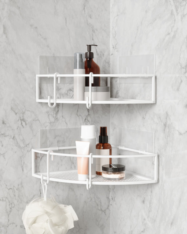 A bathroom with a white Cubiko Corner Bins, Set Of 2 featuring rust-free metal by Umbra.