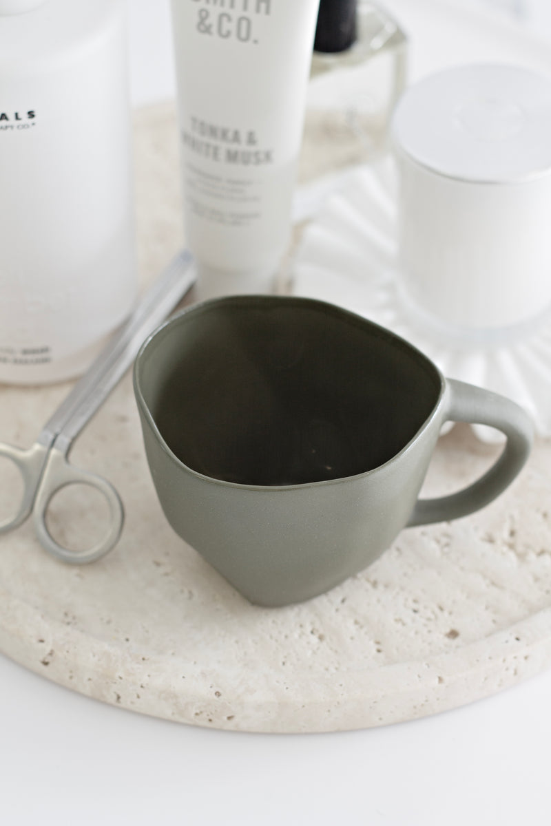 Haan stoneware coffee mug in natural finish styled on travertine tray with neutral home décor