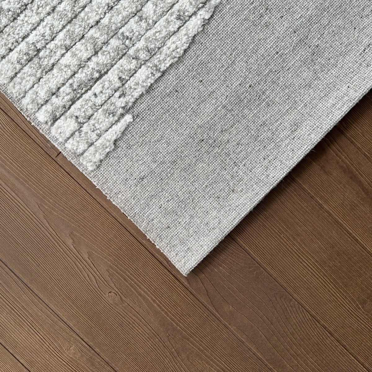 Corner of the grey and ivory rug on a dark timber floor