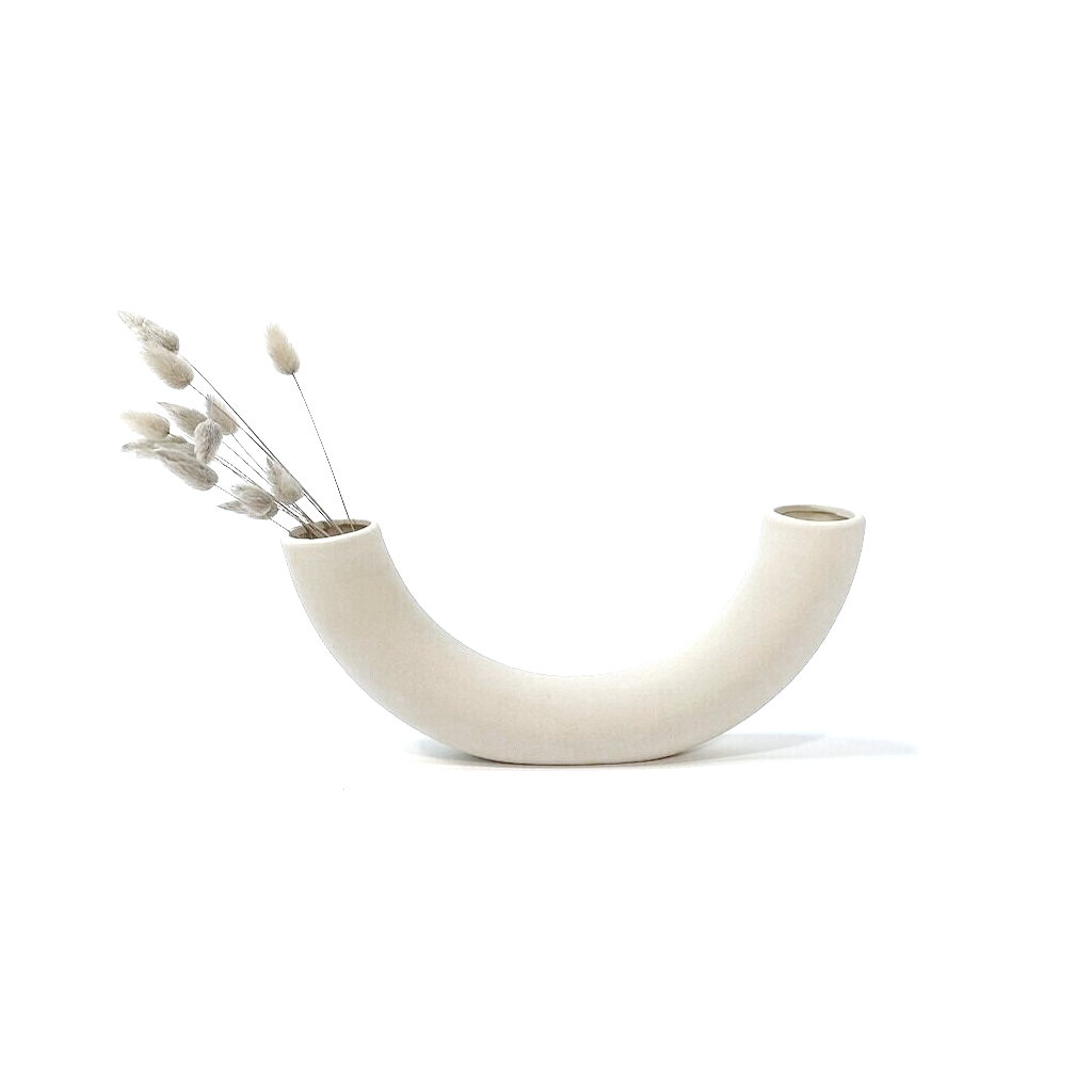 Dried bunny tail grasses arranged in one end of the half pipe vase, on a white background