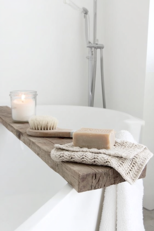 Unbleached handmade cotton face cloth styled with natural soap and a bath brush on rustic timber above a white bathtub.