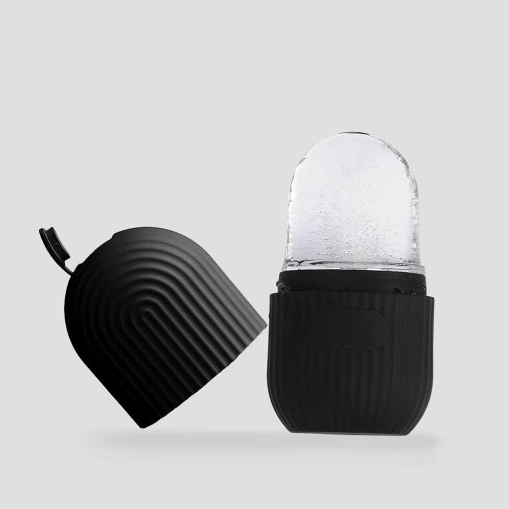 Black ice roller with its ribbed cover lifted off, the clear frosted dome visible, on a grey backdrop