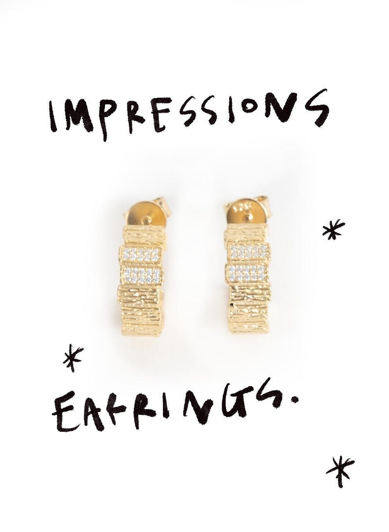 Impressions gold earrings with hand drawn lettering on white