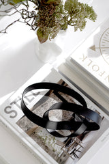 Black infinity loop metal sculpture styled on coffee table books in minimalist neutral interior