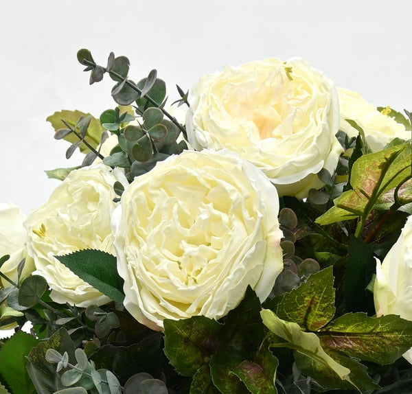 Bouquet of white roses with greenery on a light gray background