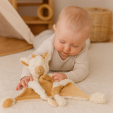 Baby playing with Juno the Giraffe comforter by Lily & George in a softly styled nursery