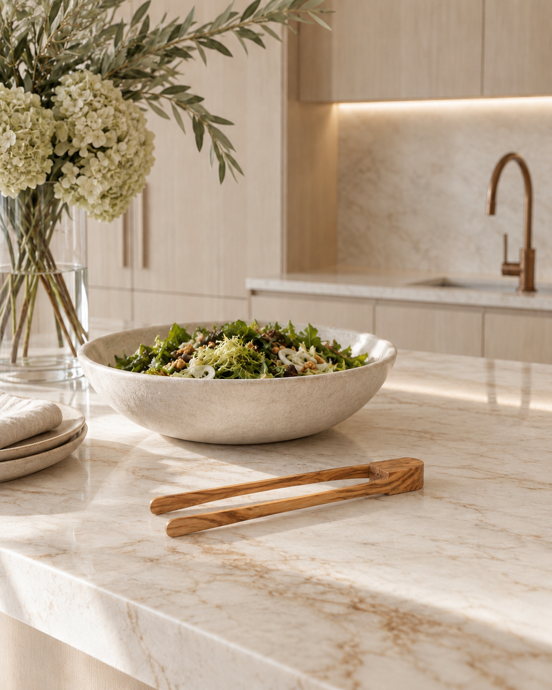 Olivewood tongs with rounded tips on a marble island in front of a salad bowl