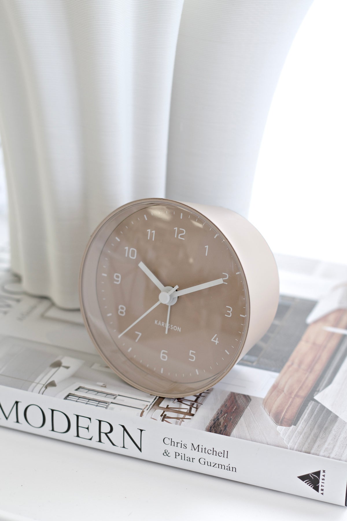 Sand Brown Cone alarm clock on a stack of design books beside a white vase