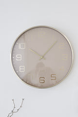 Karlsson Elegance Glow wall clock in soft brown with gold hands and a slim metallic rim on a white wall