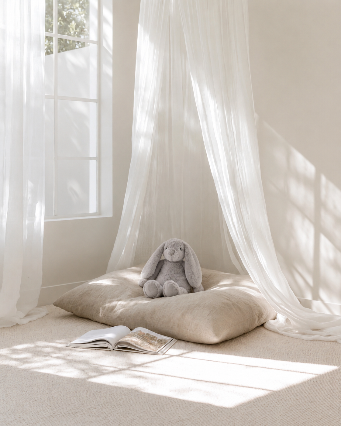 Flopsy Bunny in Silver sitting on a linen floor cushion under a sheer canopy in a sunlit kids reading nook