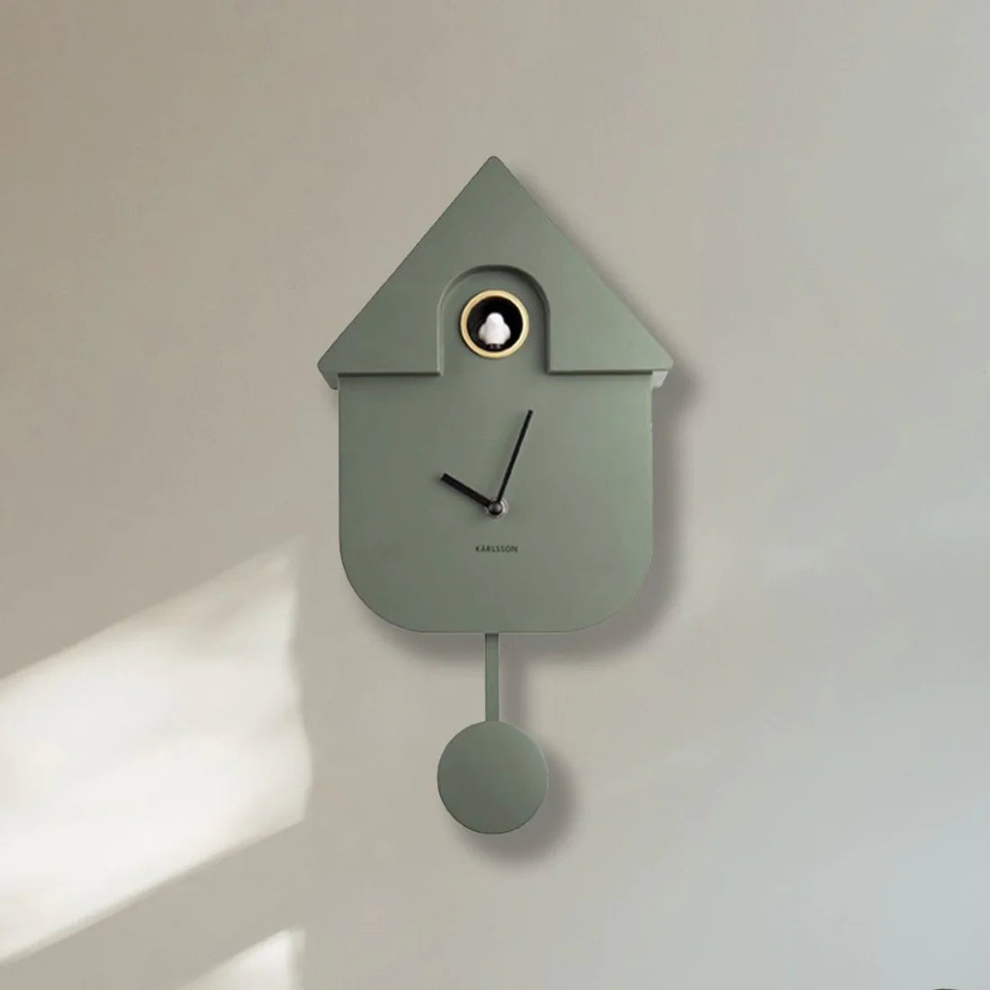 Karlsson Modern Cuckoo Clock in jungle green with a small bird detail, styled on a pale wall