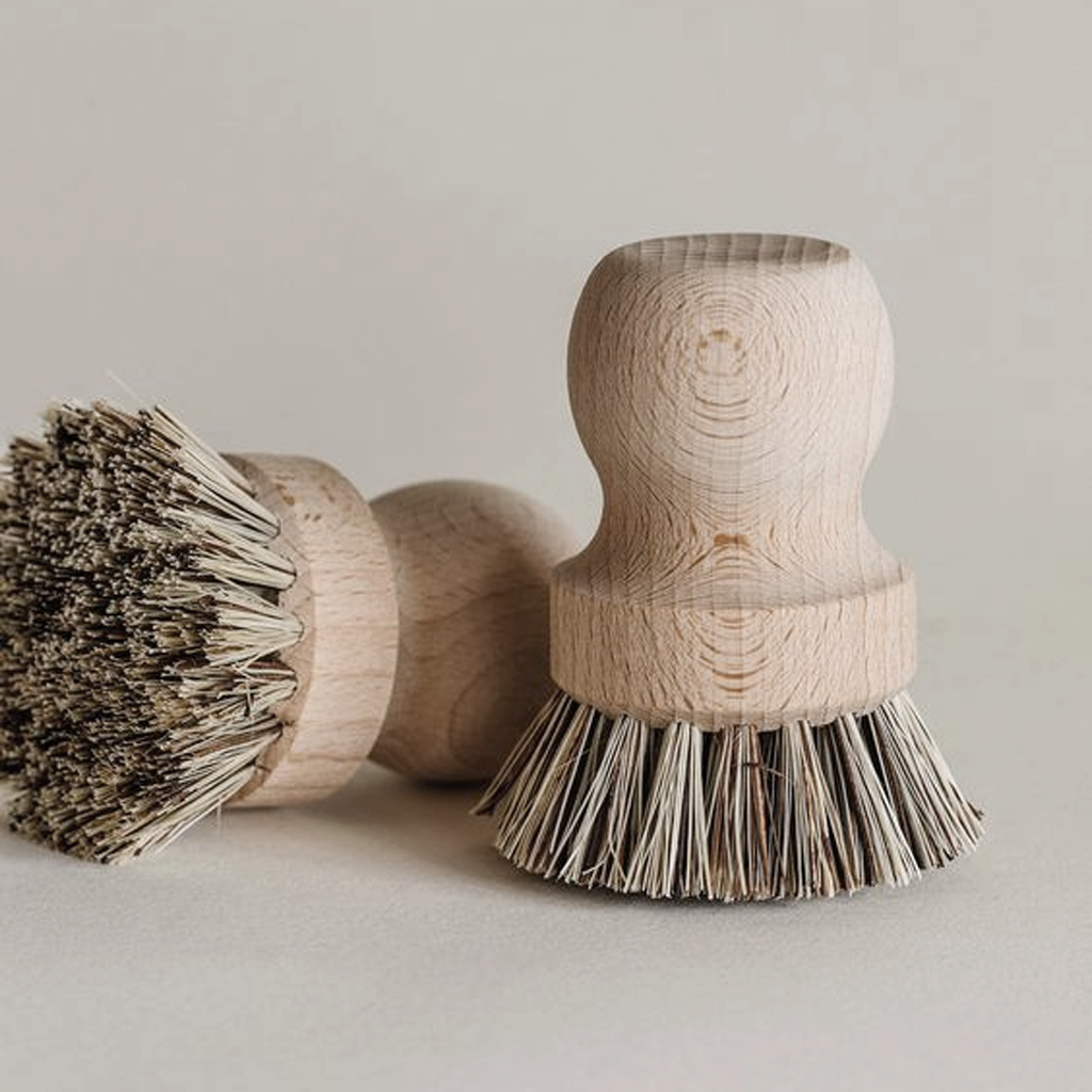 Two pot brushes, one on its side, on a pale grey surface