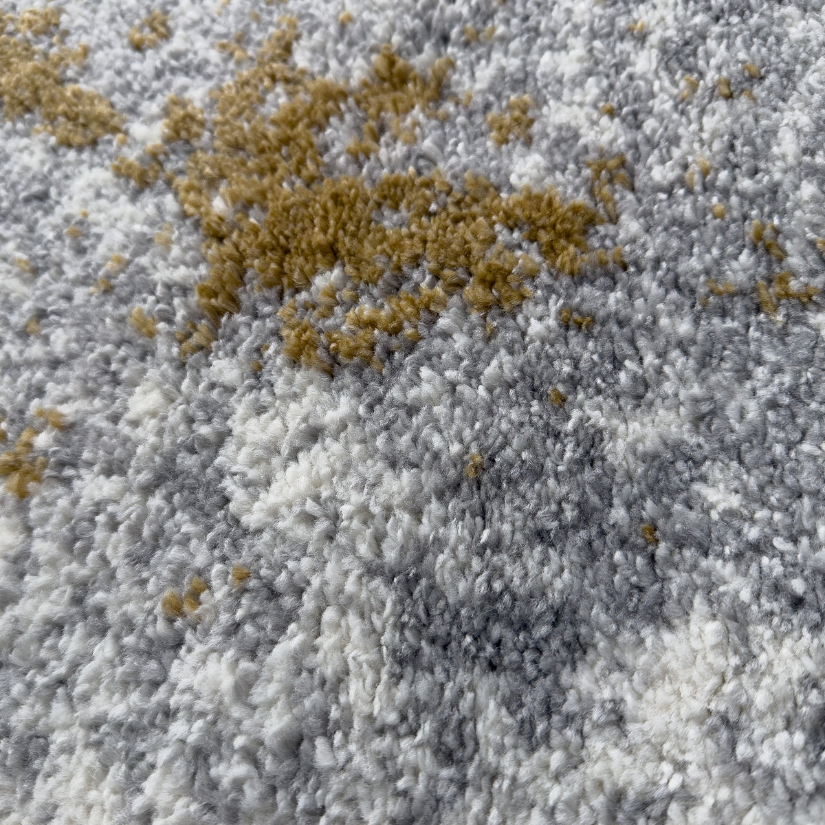 Close view of the plush pile with gold patches over grey and ivory