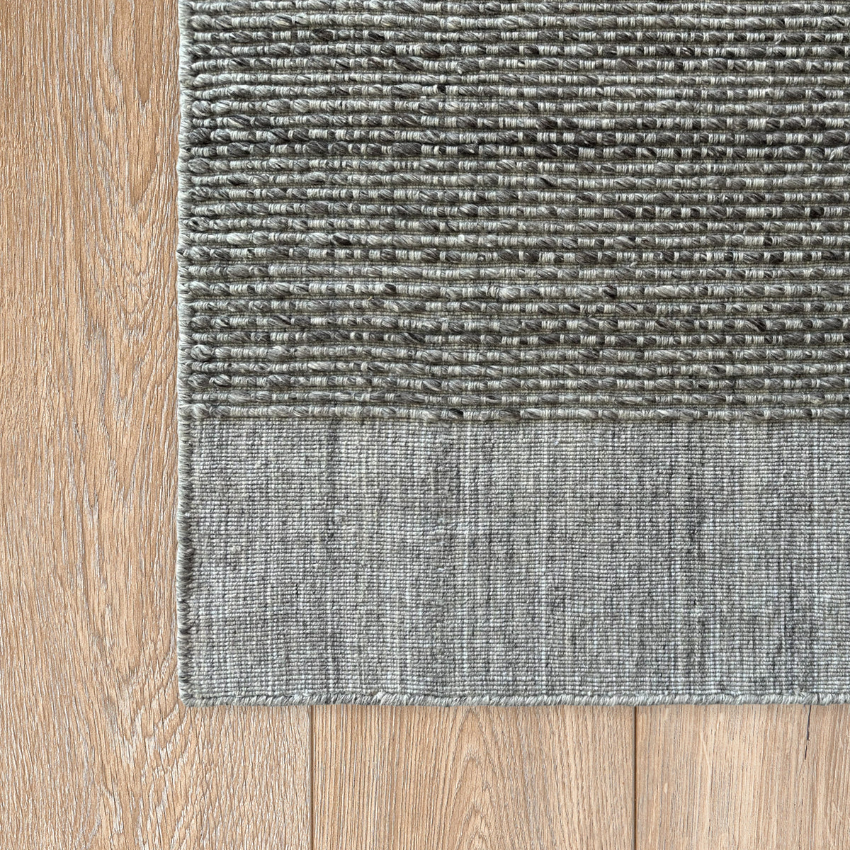 Corner of the grey ribbed rug on a light timber floor