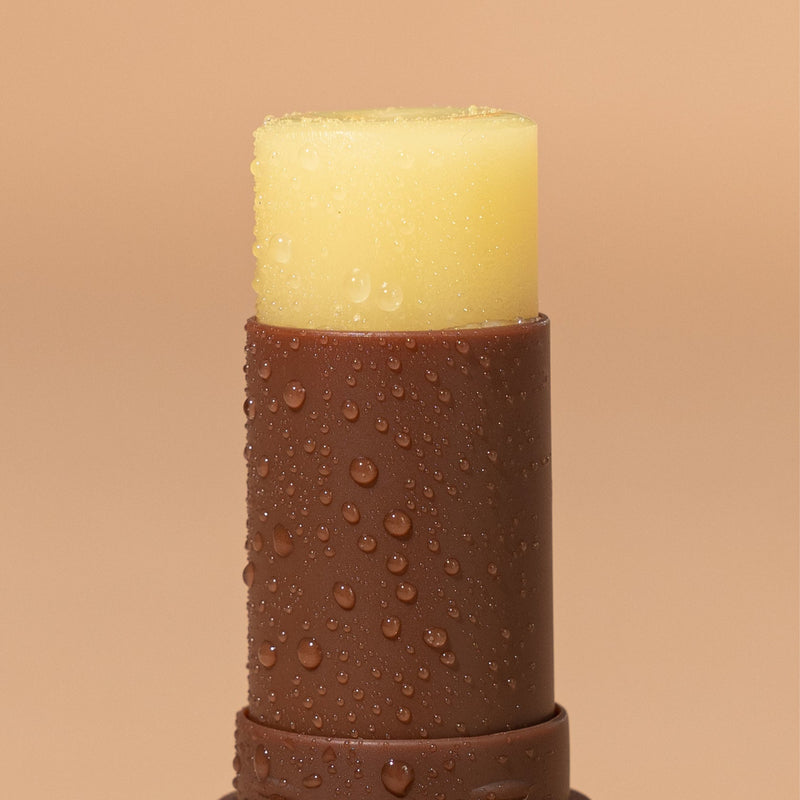 A Coconut Lip Balm SPF 50+ from We Are Feel Good Inc., with water droplets, offering protection.