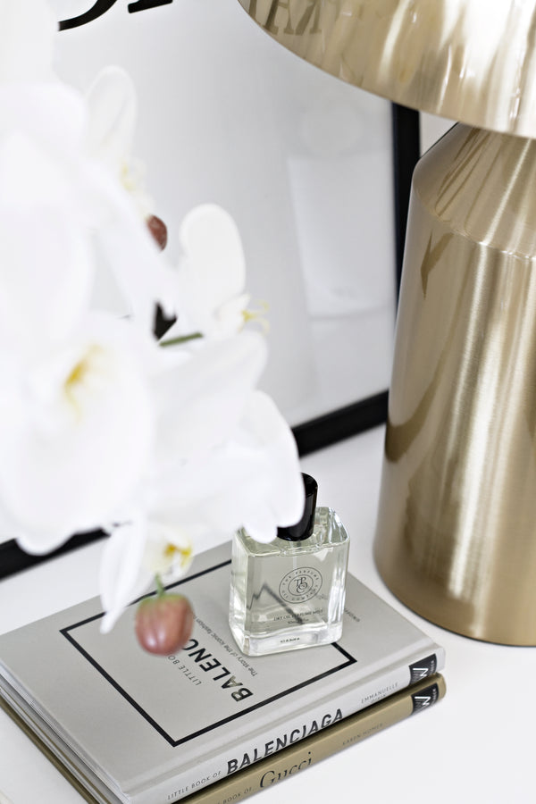 Little Book of Balenciaga styled with perfume, white orchids, and a brass lamp beside Gucci and fashion books.