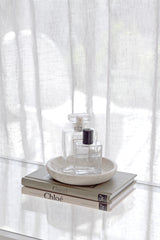 Perfume bottle on books - Little Book of Chloé and Gucci – compact fashion history book styled with perfume and coffee table decor. with a white curtain background