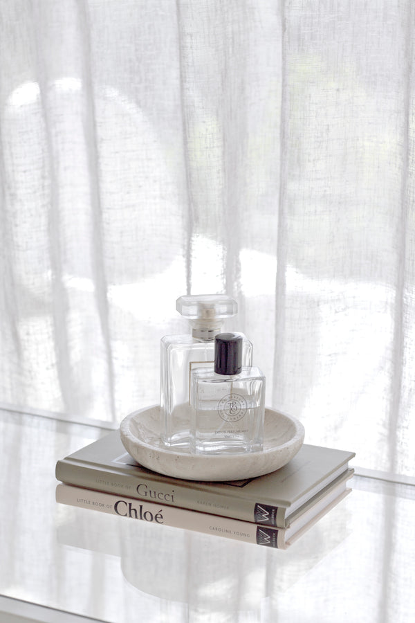 Perfume bottle on books - Little Book of Chloé and Gucci – compact fashion history book styled with perfume and coffee table decor. with a white curtain background