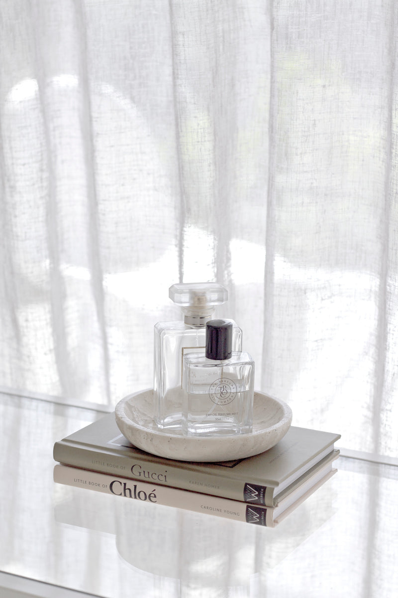 Perfume bottle on books - Little Book of Chloé and Gucci – compact fashion history book styled with perfume and coffee table decor. with a white curtain background