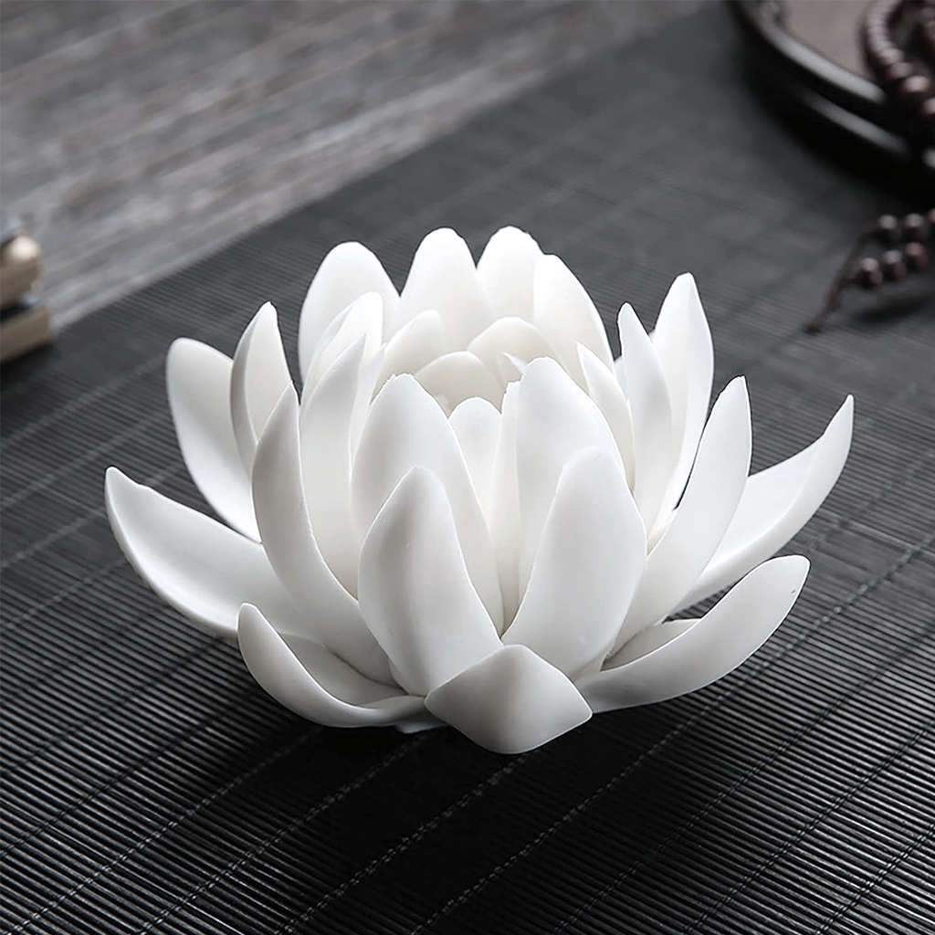 Lotus incense holder resting on a dark ribbed mat with beads and a dish blurred behind