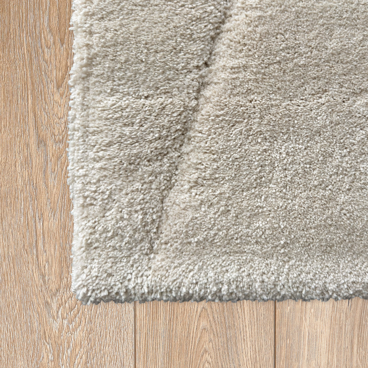 Corner of the white plush rug with etched lines on a light timber floor