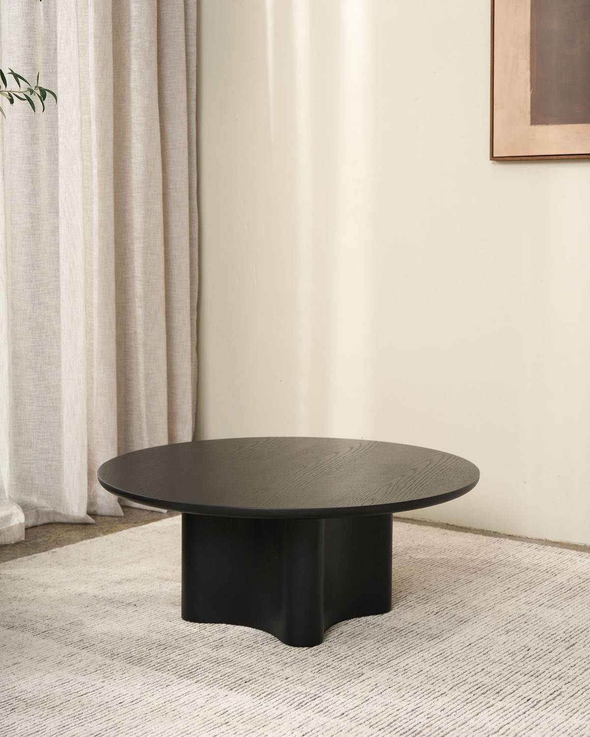 Luma Coffee Table shown in the Black Oak colour option on a pale rug by linen curtains