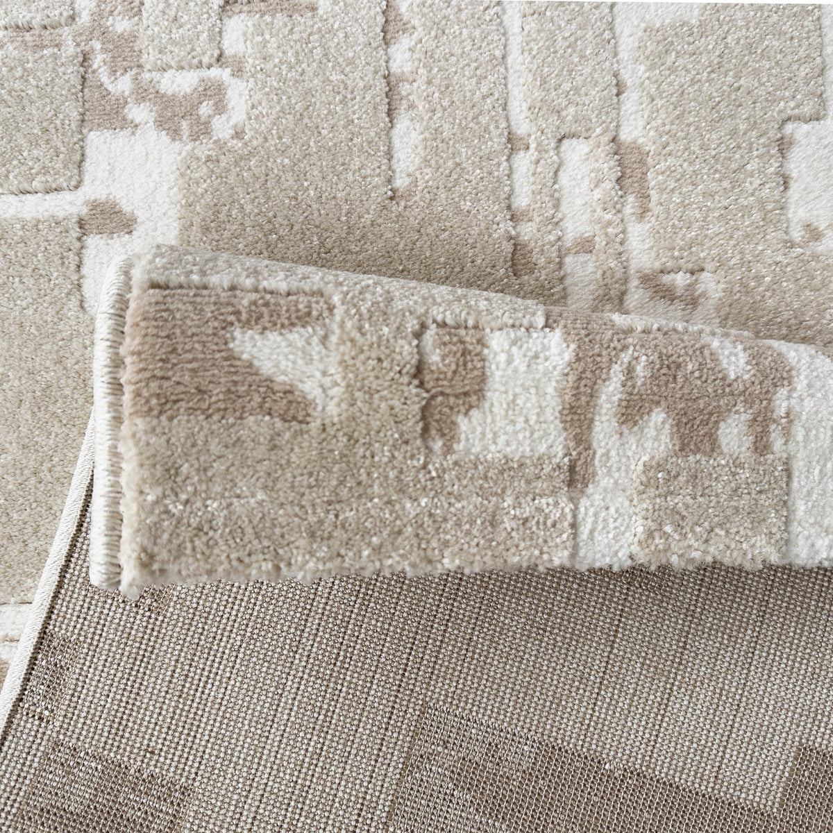 Neutral abstract rug folded back to show the woven backing