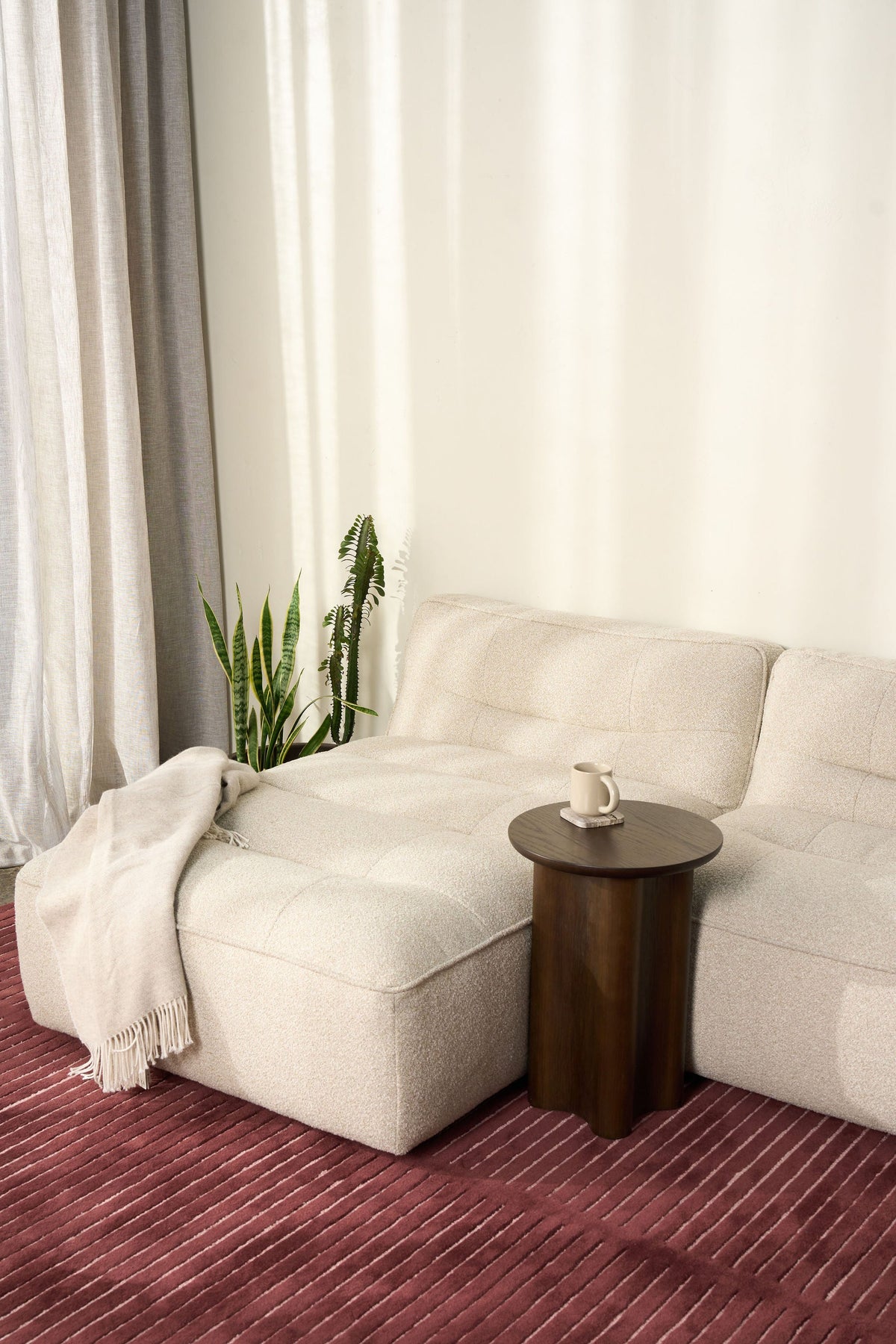 Cream boucle sofa with a draped throw and the Brown Oak Luma Side Table on a burgundy striped rug