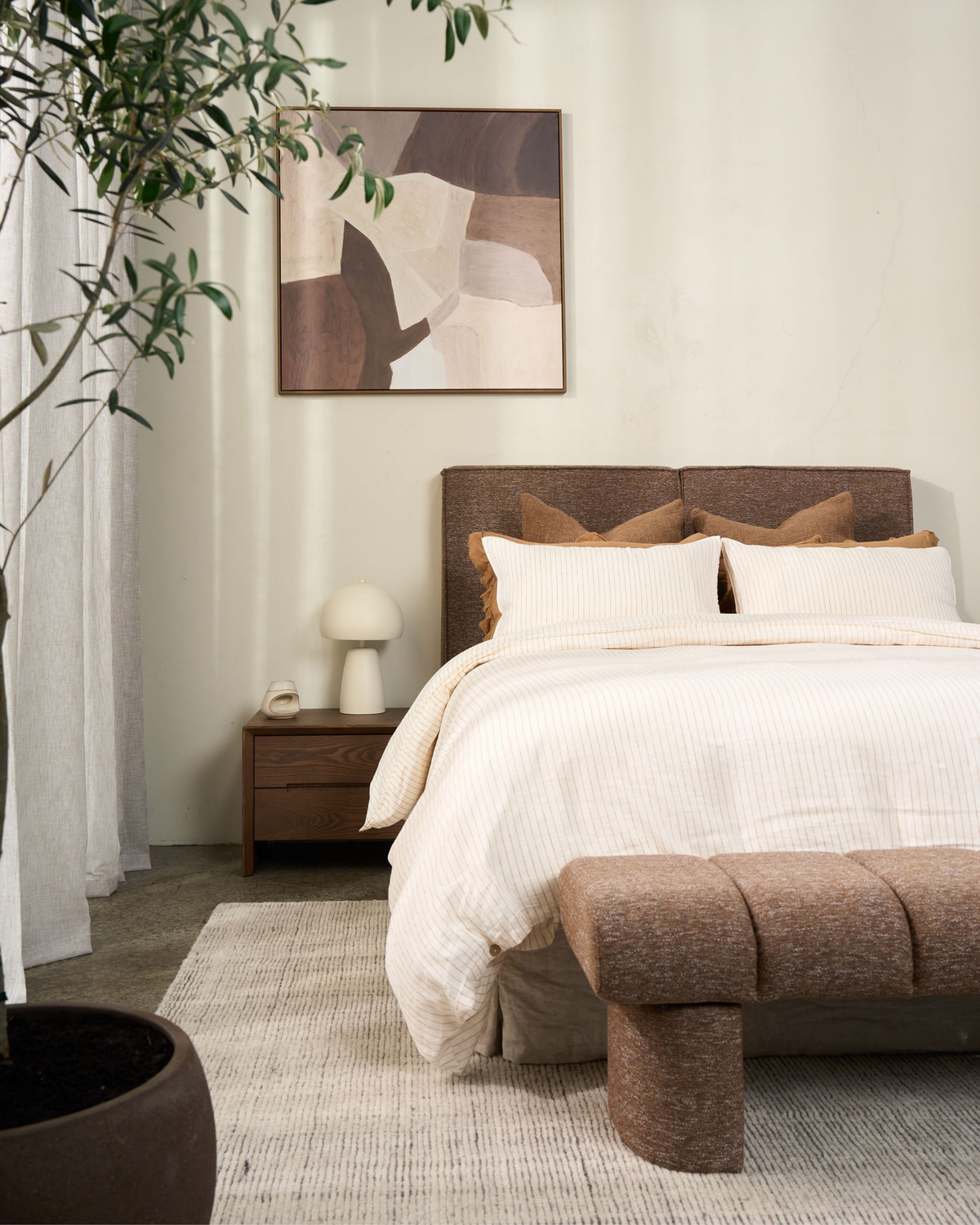 Bedroom with the Dusty Seed bench at the foot of a bed dressed in striped linen