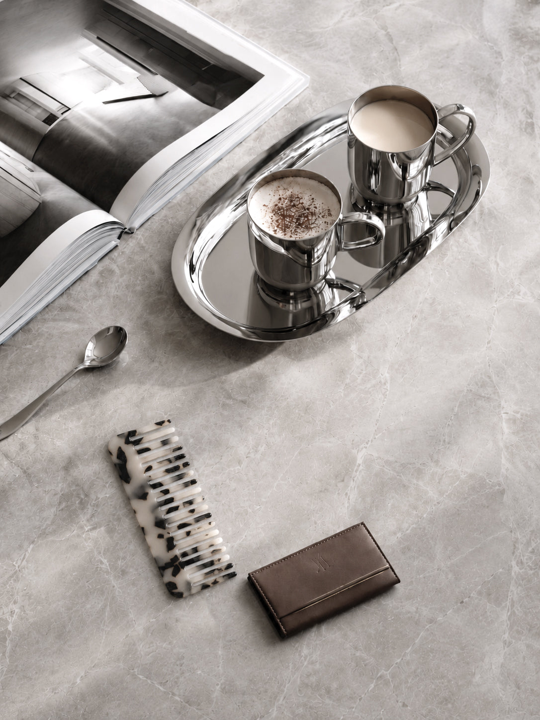 Black and white acetate comb on a marble vanity with a silver tray, candle and open magazine