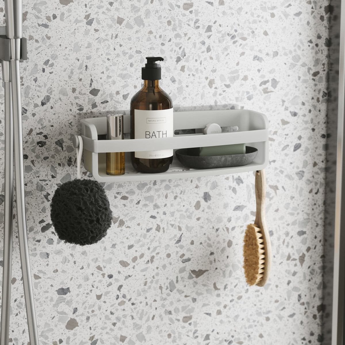 Umbra Flex shower bin in white on a terrazzo wall with a sponge and brush on its knobs