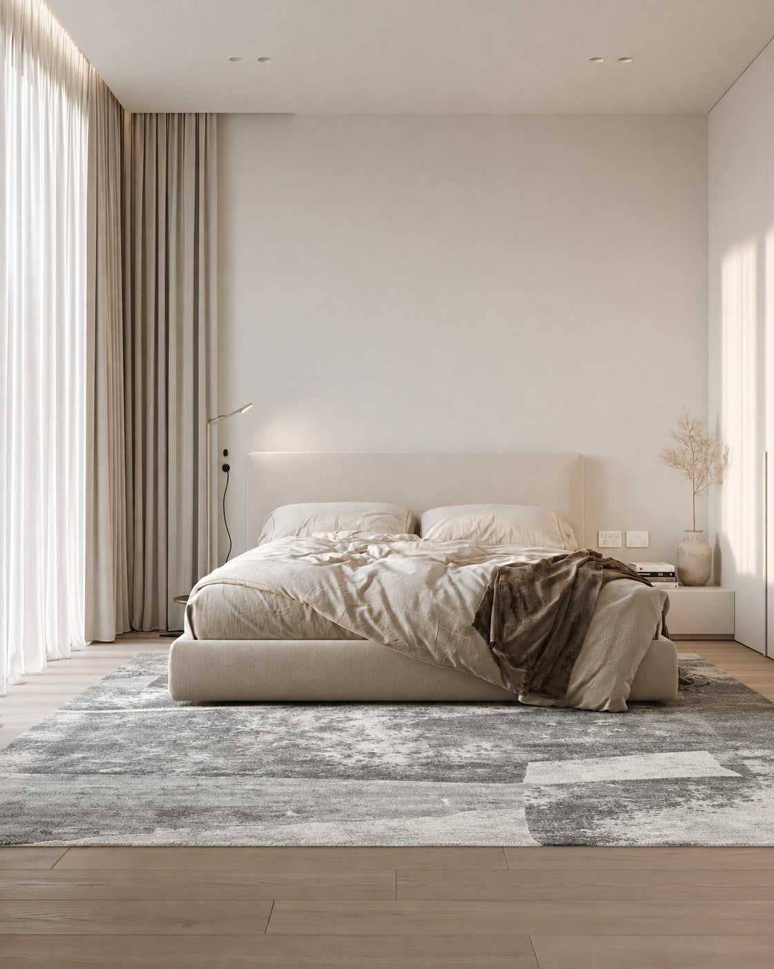 Malta Shadow Rug under a low bed with rumpled linen in a sunlit bedroom