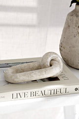 Marble loop sculpture styled on coffee table book with natural stone vase