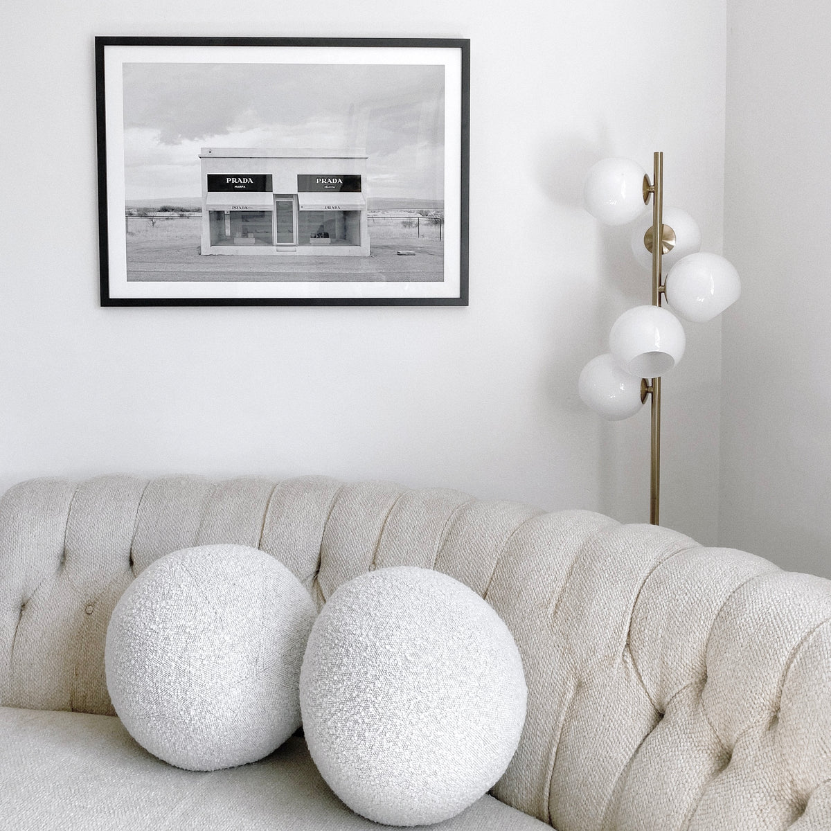 Marfa print in a black frame above a cream tufted sofa with round cushions