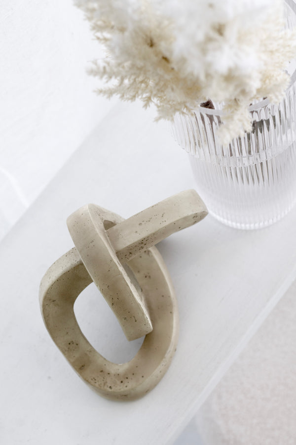 Marley Decorative Link Sculpture in sandy resin styled with clear ribbed vase and white florals on shelf – modern minimal look