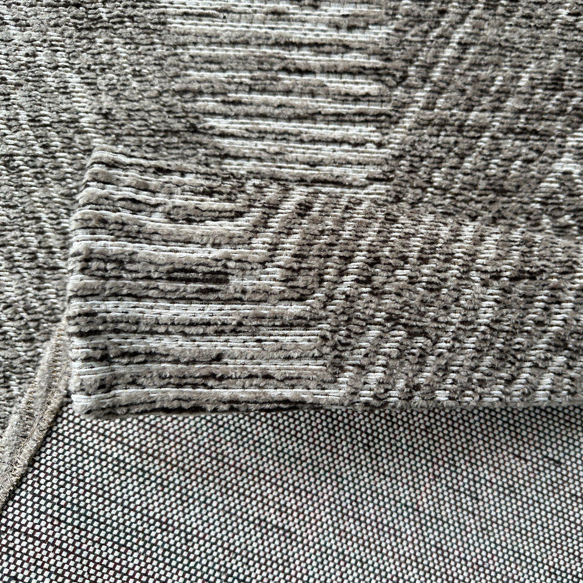 Brown chenille rug folded back to show its woven backing
