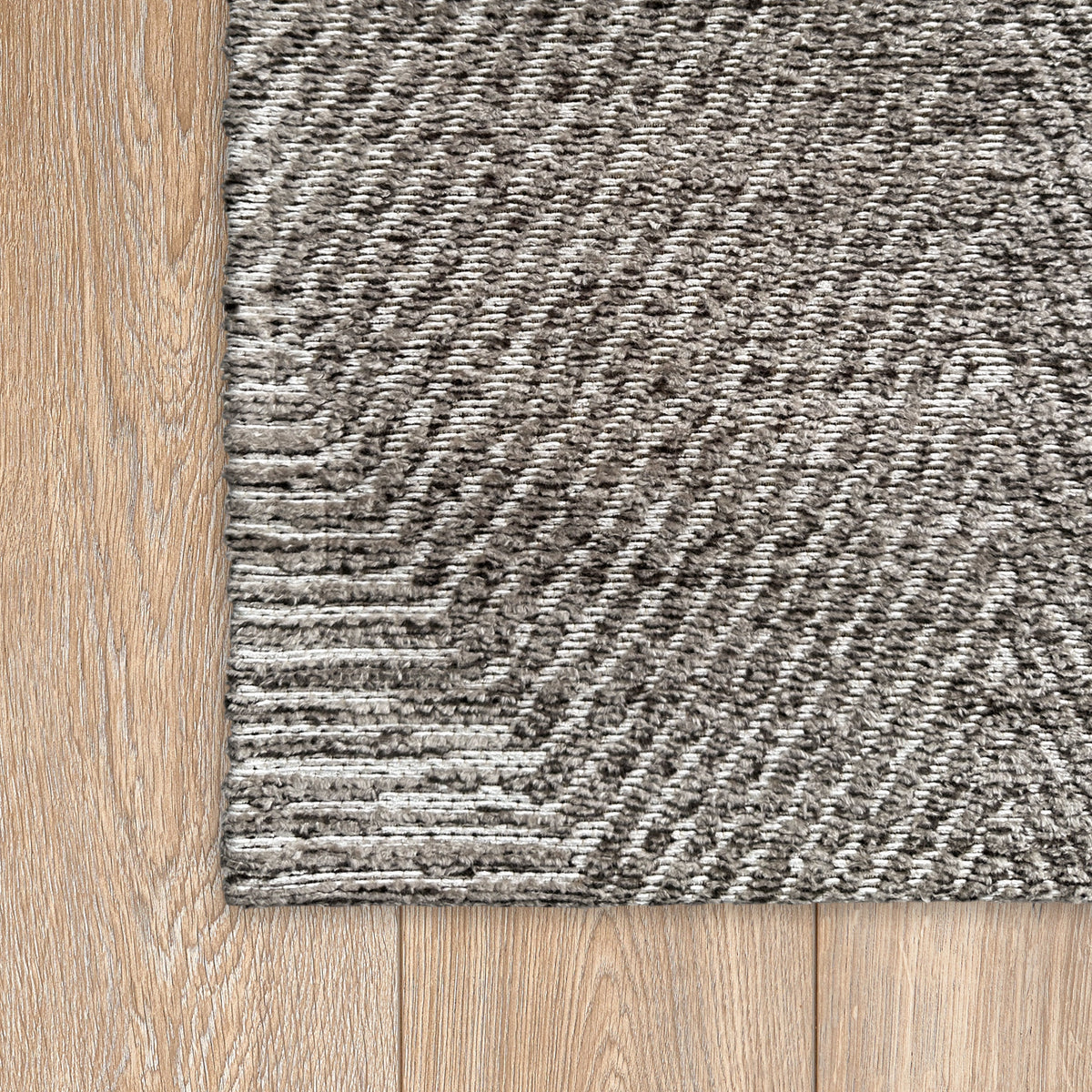 Corner of the brown chenille rug on a light timber floor