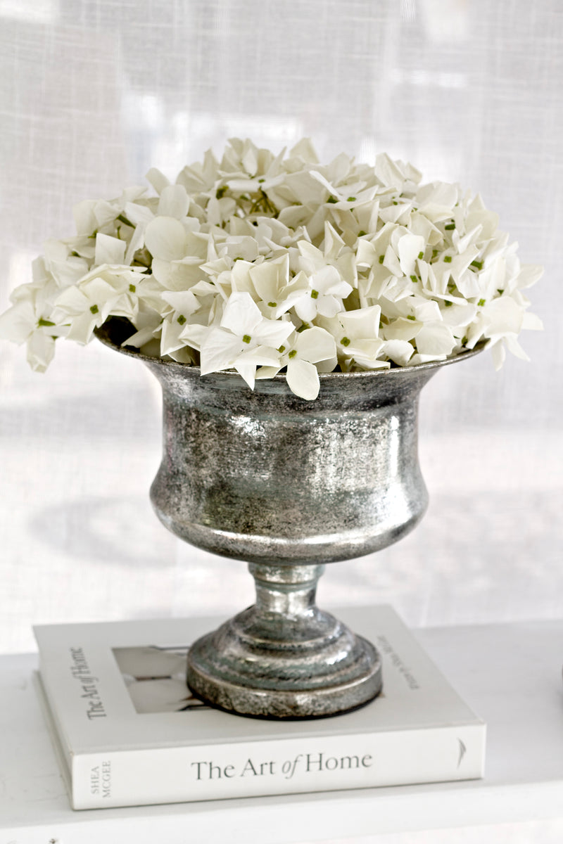 Marseille pewter urn planter styled with white faux flowers, displayed on “The Art of Home” book, elegant decorative vessel for classic interiors.