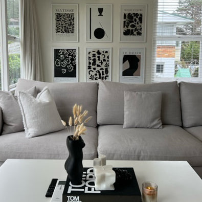 Matisse print in a monochrome gallery wall above a grey sofa and coffee table