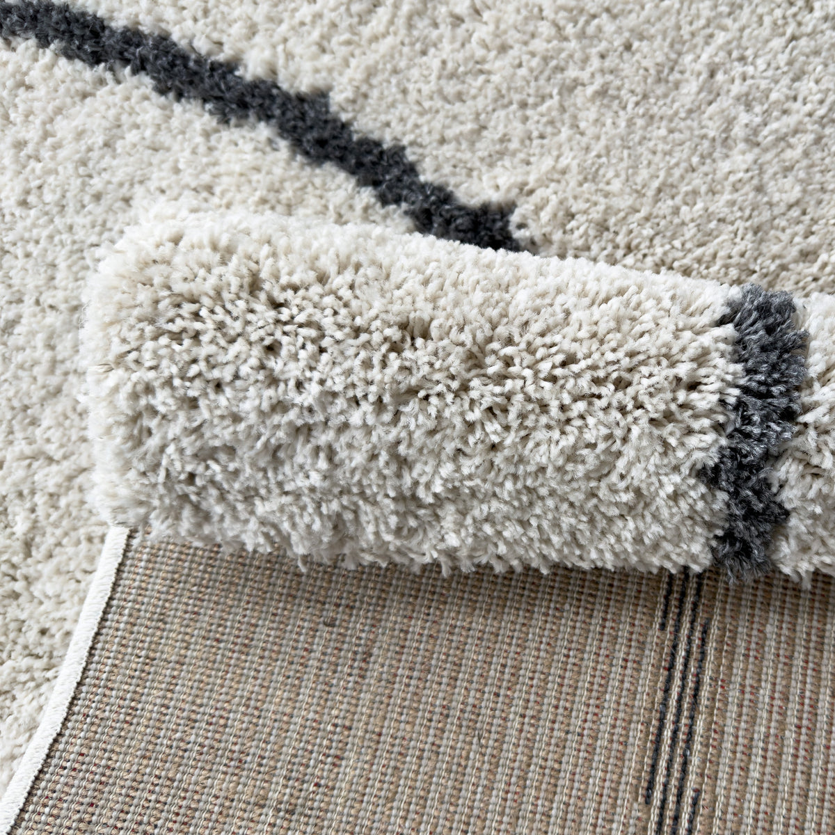 Rolled edge of the white plush rug showing the pile height and backing
