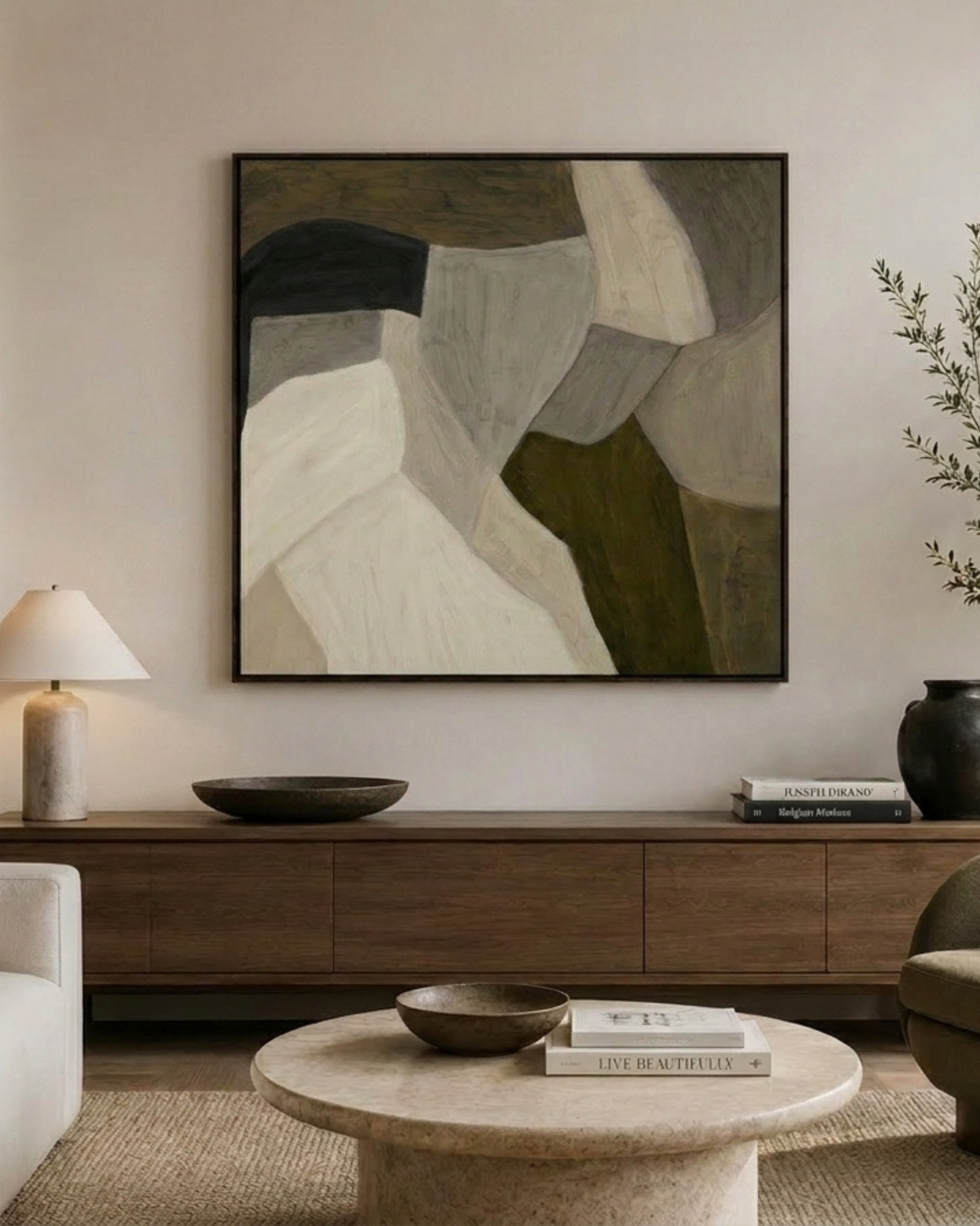 Mess Print above a walnut sideboard with a stone table lamp, dark bowl and vase, and a round travertine coffee table