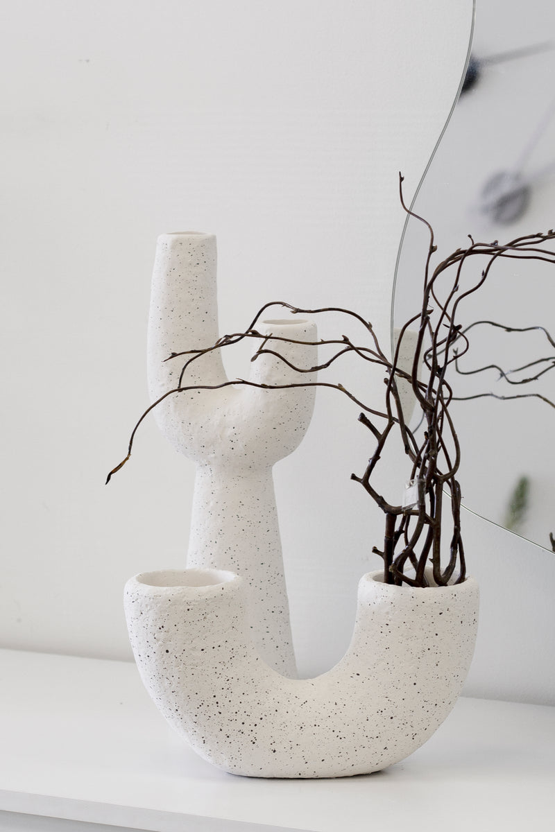 Mia off-white speckled pipe vase styled with sculptural branches beside a curved mirror on a white console.