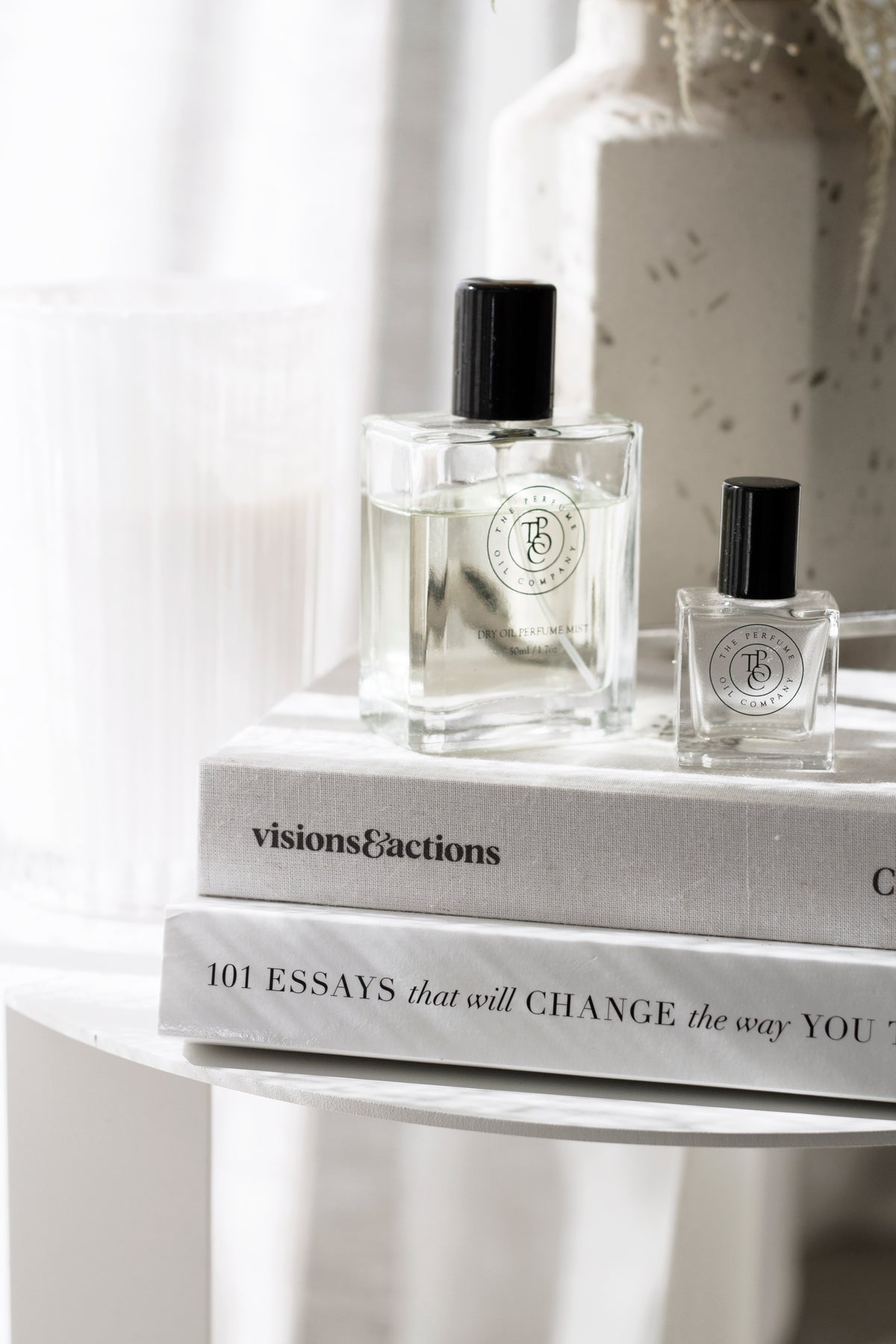 Midnight perfume oil and dry oil mist styled on neutral books with ceramic decor