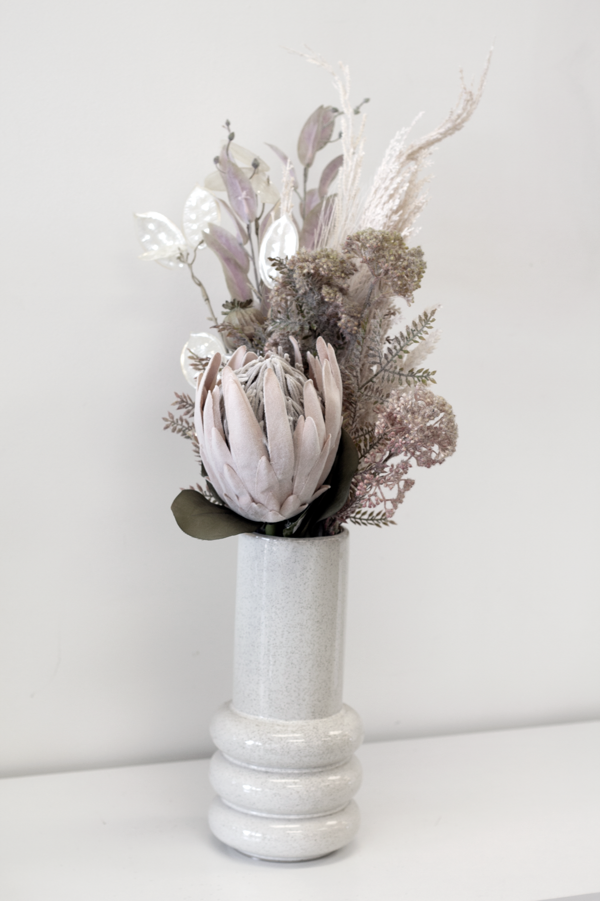 Milan Vase holding a dried protea and native bouquet against a white wall