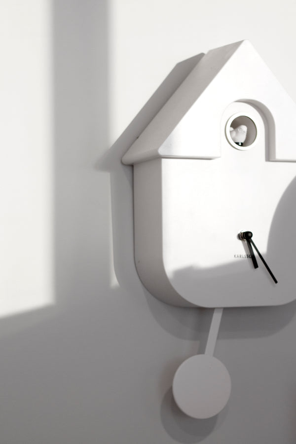 Karlsson Modern Cuckoo Clock in white with pendulum detail, styled on wall with minimalist shadows; Scandinavian home décor.