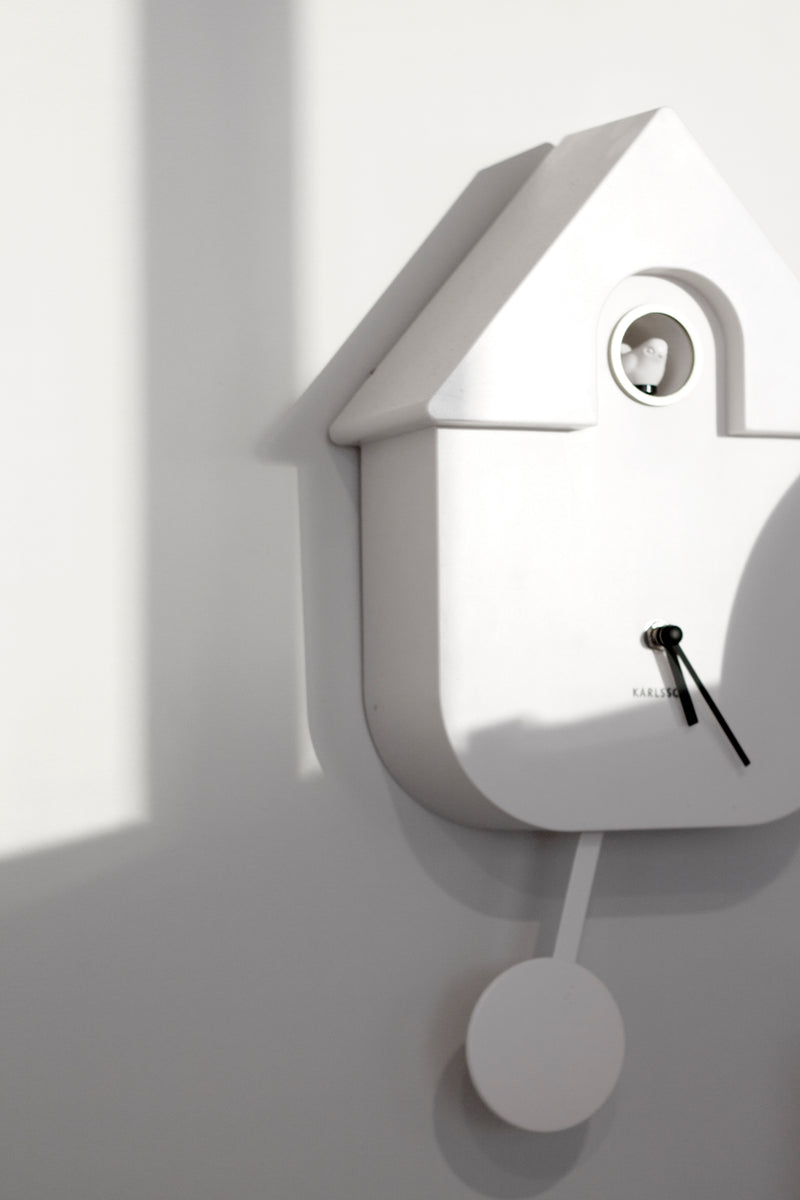 Karlsson Modern Cuckoo Clock in white with pendulum detail, styled on wall with minimalist shadows; Scandinavian home décor.