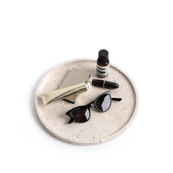 Light travertine round tray styled with soaps and dropper bottles