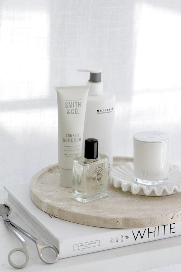 Round travertine tray in natural beige styled with candle, perfume, and skincare; minimalist decor organiser.
